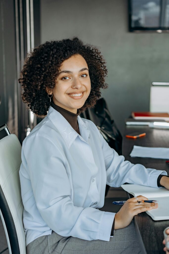 Bright and confident woman smiling at her desk in a modern office environment.
