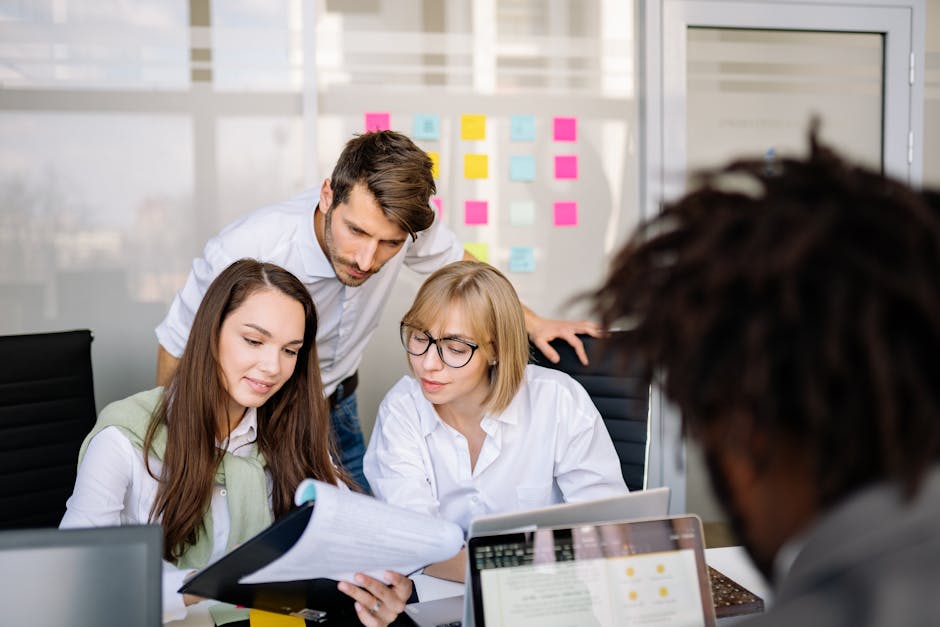 A diverse team of professionals collaborating on paperwork in a modern office setting.
